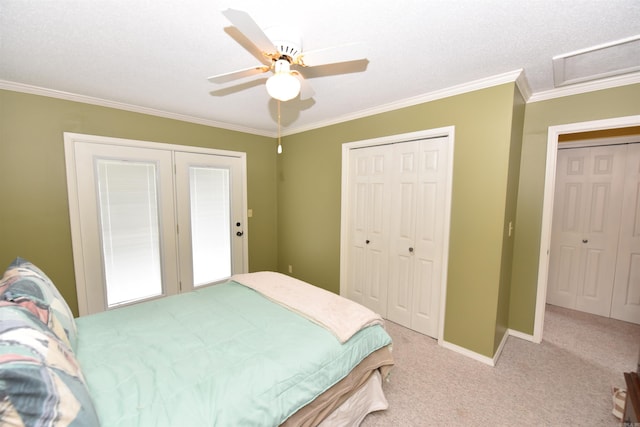 carpeted bedroom featuring a textured ceiling, ceiling fan, crown molding, and two closets