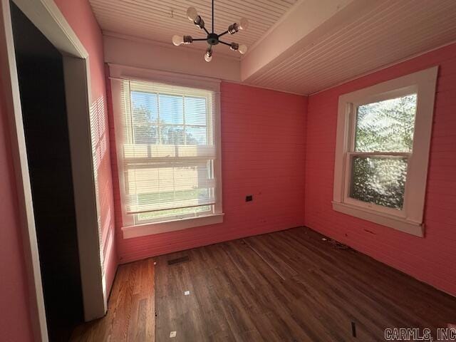 spare room with hardwood / wood-style flooring, a notable chandelier, and a healthy amount of sunlight