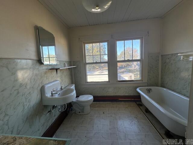 bathroom with sink, toilet, tile walls, and a tub