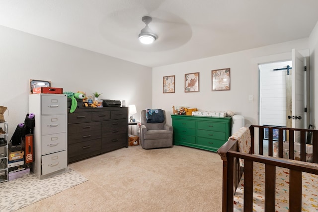 bedroom featuring ceiling fan, light colored carpet, and a nursery area