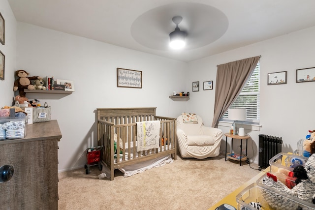 bedroom featuring ceiling fan, radiator heating unit, carpet floors, and a nursery area