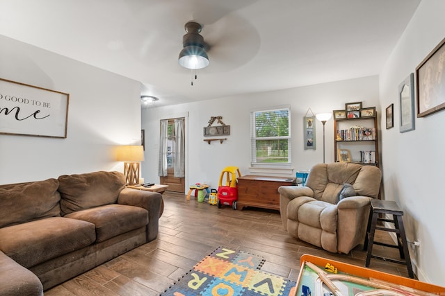 living room featuring ceiling fan and dark wood-type flooring