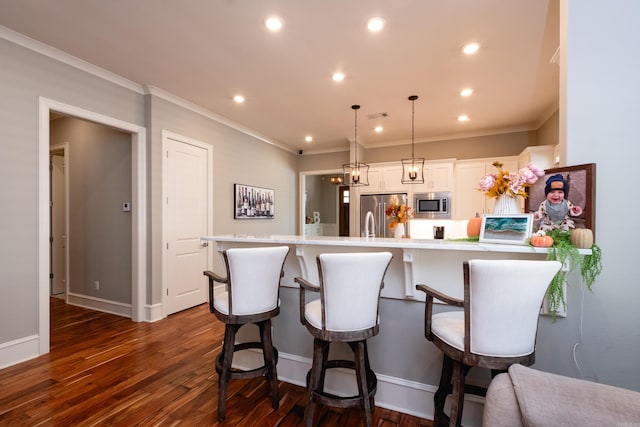 kitchen featuring white cabinetry, hanging light fixtures, stainless steel appliances, dark hardwood / wood-style flooring, and crown molding