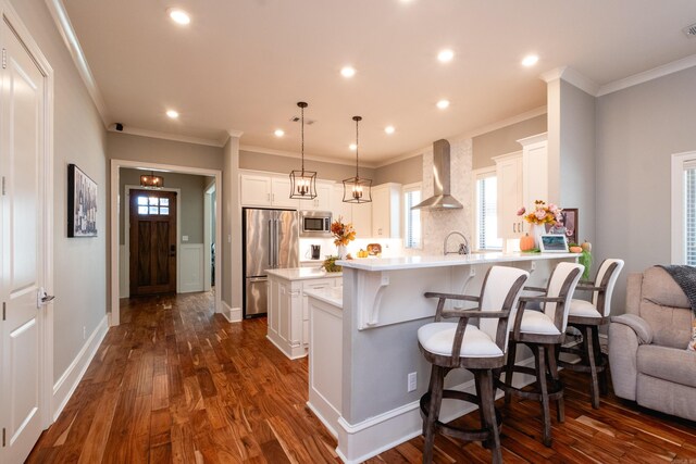 kitchen with pendant lighting, dark wood-type flooring, white cabinets, built in appliances, and wall chimney exhaust hood