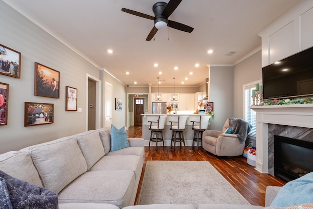 living room with ceiling fan, dark hardwood / wood-style flooring, a premium fireplace, and ornamental molding