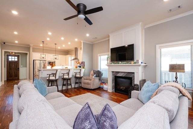 living room with ornamental molding, ceiling fan, sink, a premium fireplace, and dark hardwood / wood-style floors