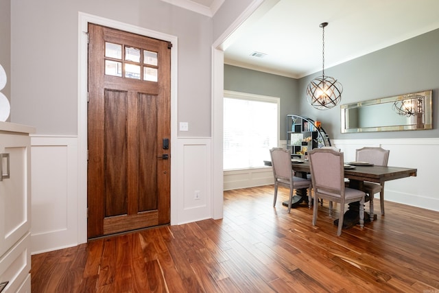 foyer entrance with a notable chandelier, wood-type flooring, and ornamental molding