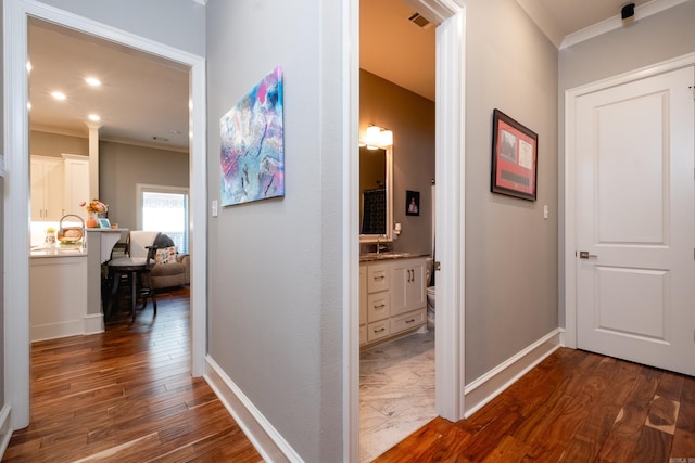 hall with sink, ornamental molding, and dark wood-type flooring