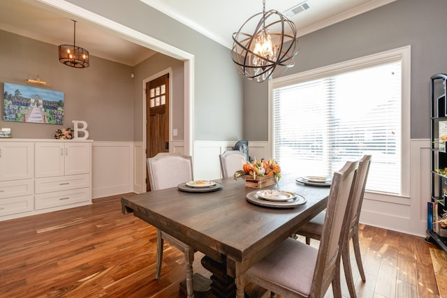 dining area featuring hardwood / wood-style floors, ornamental molding, and a notable chandelier