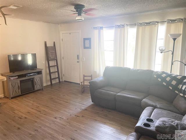 living room with ceiling fan, a textured ceiling, and hardwood / wood-style flooring