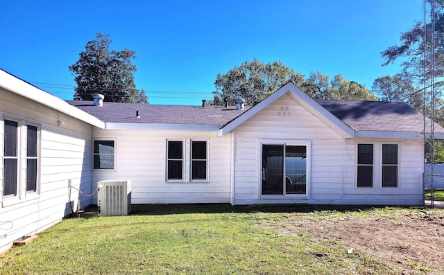 back of house with central AC unit and a lawn