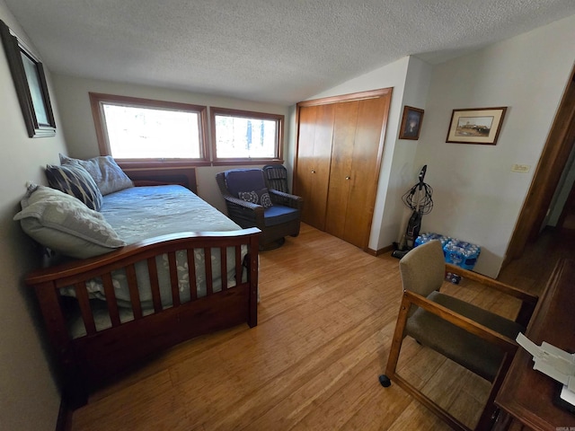 bedroom featuring a closet, light hardwood / wood-style flooring, and a textured ceiling