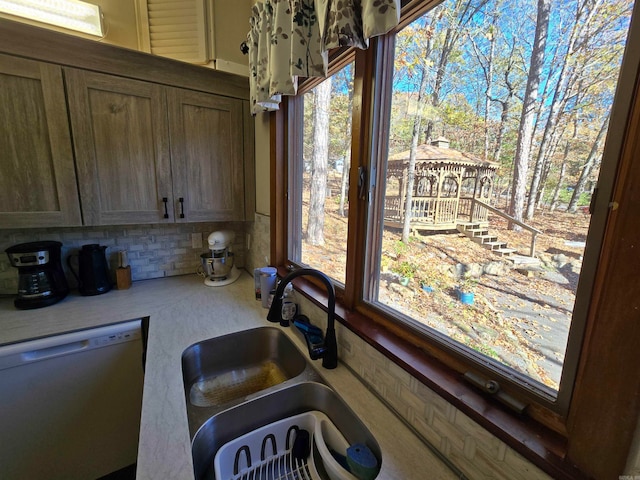 kitchen featuring decorative backsplash, dishwasher, and sink