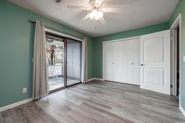 unfurnished bedroom featuring a textured ceiling, light wood-type flooring, access to outside, and ceiling fan