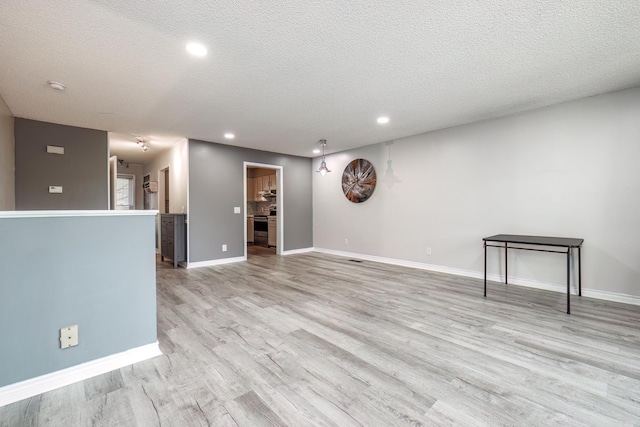 unfurnished living room featuring a textured ceiling and light hardwood / wood-style flooring