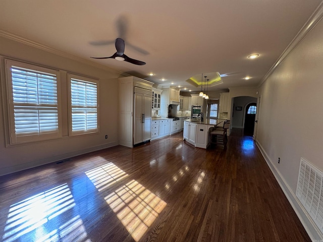 kitchen featuring a breakfast bar, hanging light fixtures, dark hardwood / wood-style floors, ornamental molding, and a kitchen island