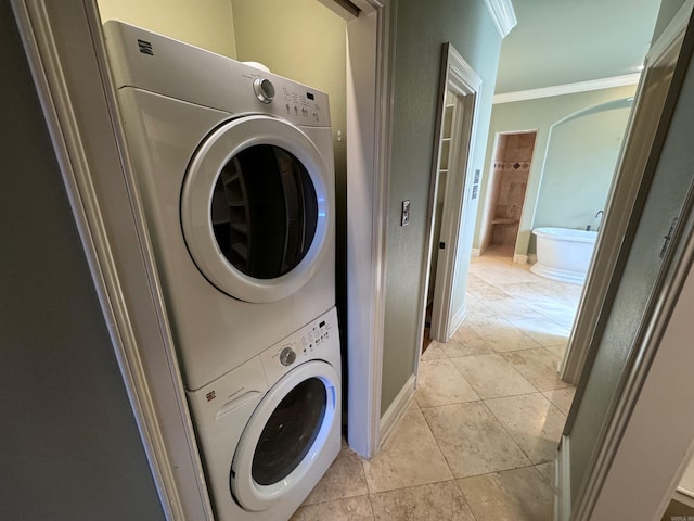 laundry area with light tile patterned flooring, ornamental molding, and stacked washer / dryer