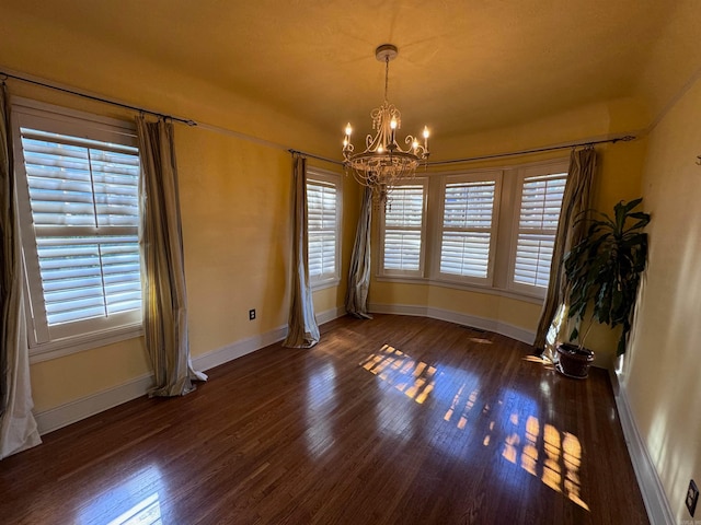 unfurnished dining area with dark hardwood / wood-style floors and a notable chandelier