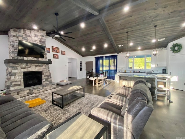 living room featuring wooden ceiling, a stone fireplace, sink, vaulted ceiling with beams, and ceiling fan