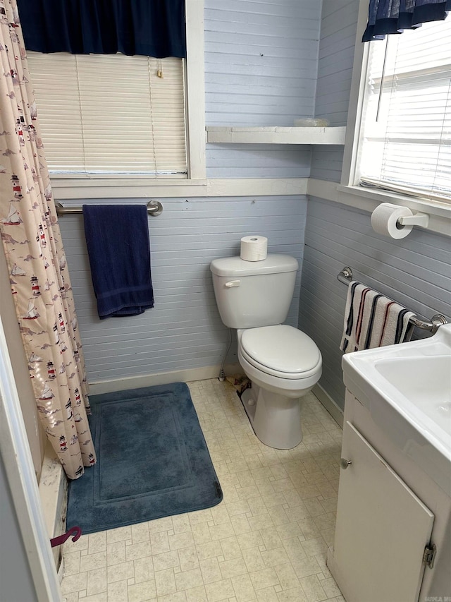 bathroom with vanity, toilet, and wooden walls