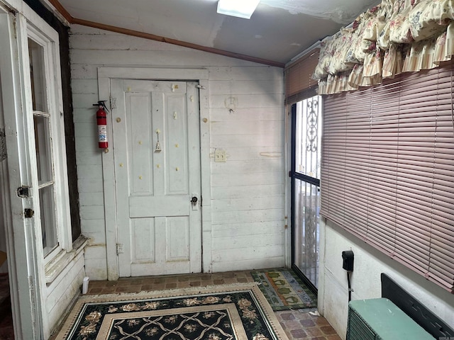 entrance foyer with wooden walls and vaulted ceiling