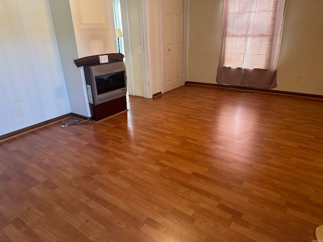 unfurnished living room featuring hardwood / wood-style flooring and heating unit