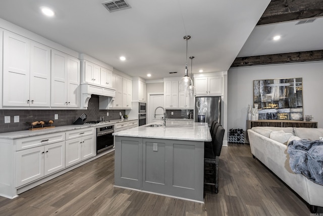 kitchen with dark hardwood / wood-style flooring, white cabinetry, sink, and a kitchen island with sink