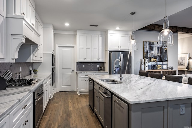 kitchen with backsplash, a kitchen island with sink, dark hardwood / wood-style flooring, white cabinetry, and stainless steel appliances