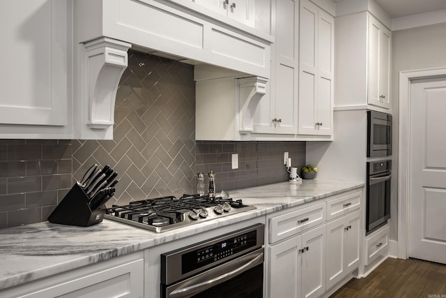 kitchen with appliances with stainless steel finishes, dark hardwood / wood-style flooring, tasteful backsplash, and white cabinetry