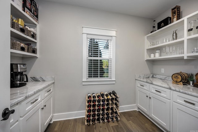 bar with white cabinetry, dark hardwood / wood-style flooring, and light stone counters