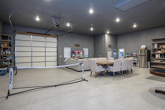 garage with stainless steel fridge and a garage door opener