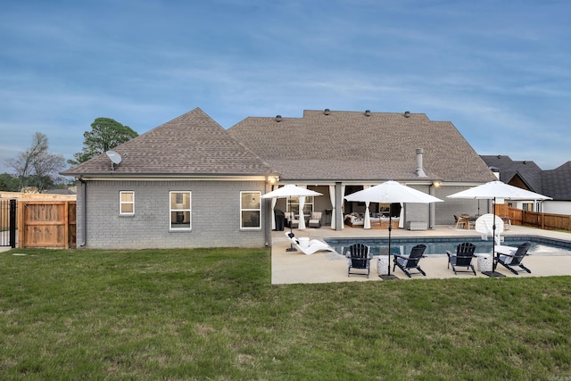 rear view of house with a lawn, a patio area, and a fenced in pool