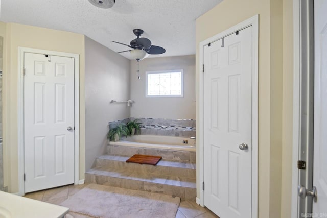 bathroom featuring tile patterned flooring, a textured ceiling, a relaxing tiled tub, and ceiling fan