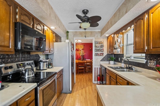 kitchen with a textured ceiling, stainless steel appliances, light hardwood / wood-style floors, and sink