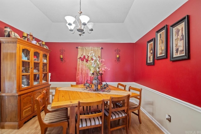 dining room featuring light wood-type flooring, vaulted ceiling, and a notable chandelier