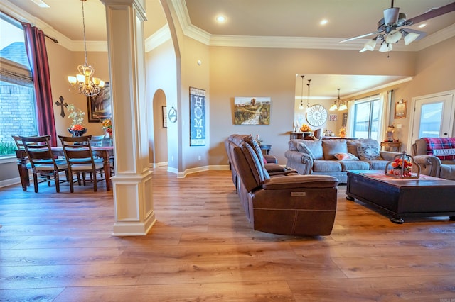 living room featuring a wealth of natural light, crown molding, wood-type flooring, and ceiling fan with notable chandelier