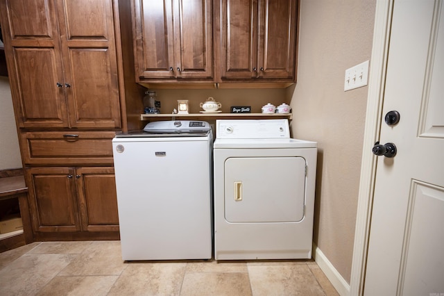 clothes washing area featuring washing machine and clothes dryer and cabinets