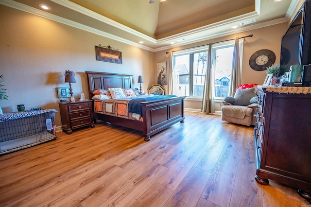 bedroom featuring a raised ceiling, light hardwood / wood-style flooring, and crown molding