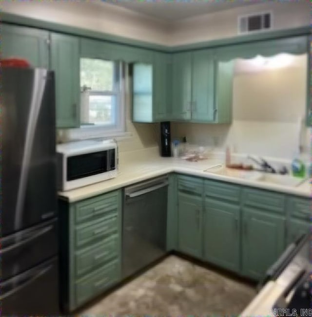 kitchen with sink, stainless steel fridge, green cabinets, and black dishwasher