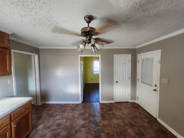 unfurnished dining area with ceiling fan, crown molding, and a textured ceiling