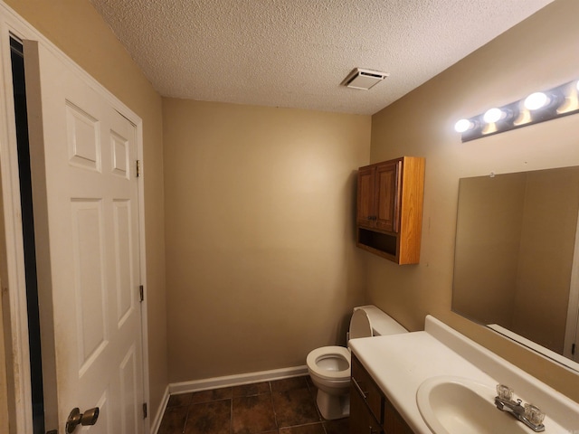 bathroom featuring toilet, vanity, a textured ceiling, and tile patterned floors