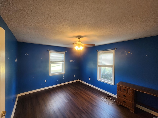 empty room with plenty of natural light, a textured ceiling, and dark wood-type flooring