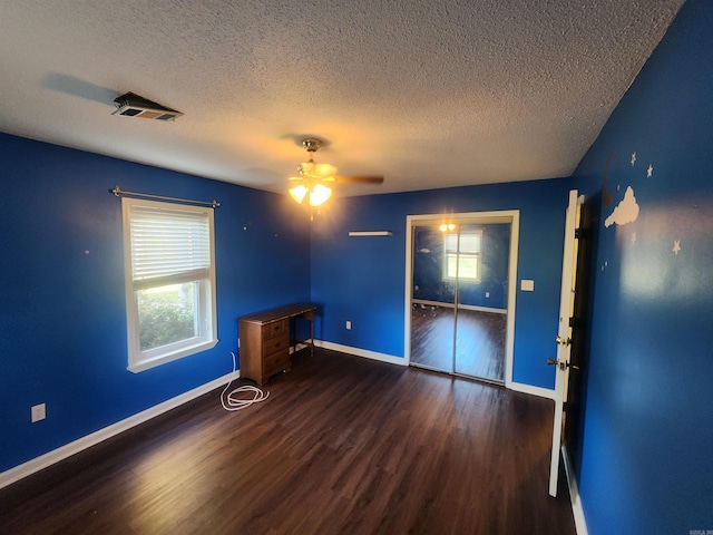 spare room featuring ceiling fan, dark wood-type flooring, and a textured ceiling