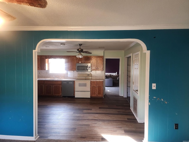 kitchen with dark hardwood / wood-style floors, ornamental molding, backsplash, and appliances with stainless steel finishes