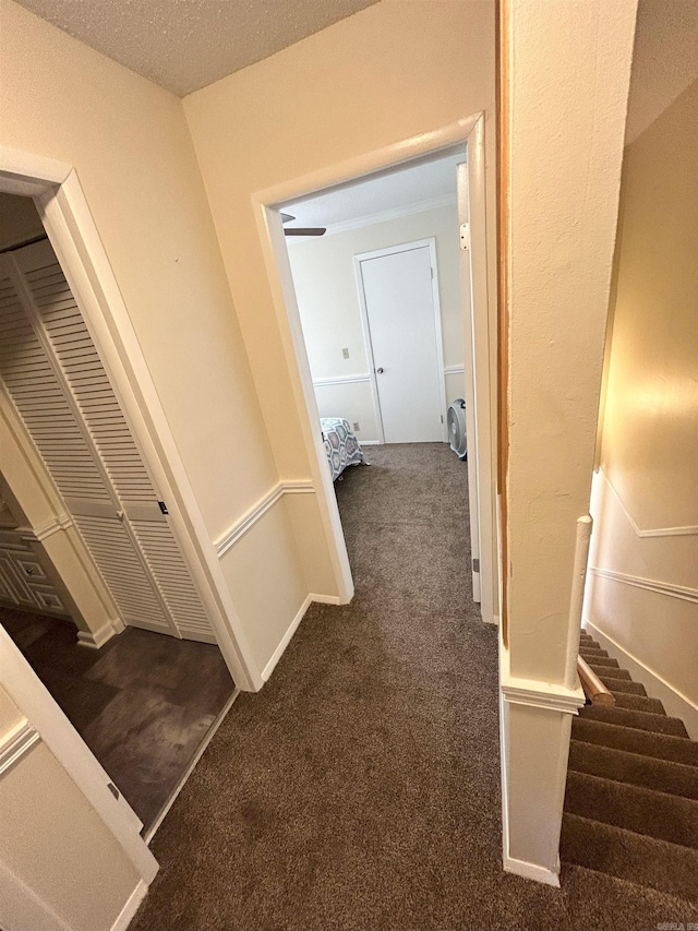 corridor with a textured ceiling and dark carpet