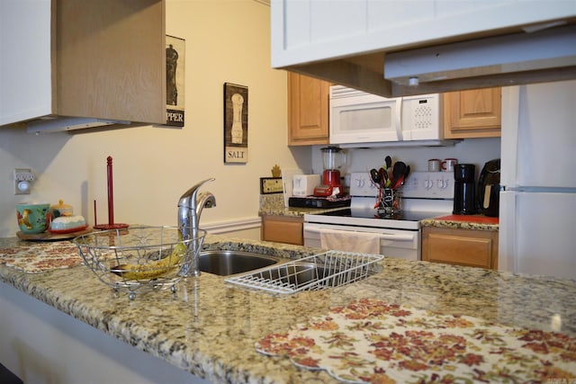 kitchen with light brown cabinets, light stone counters, and white appliances