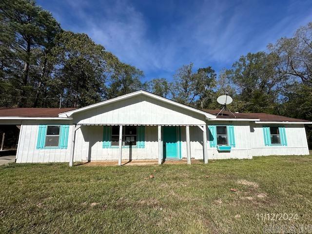 rear view of house featuring a carport, a porch, and a yard