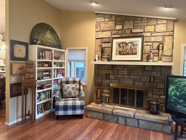 living area featuring a textured ceiling, wood-type flooring, a fireplace, and vaulted ceiling