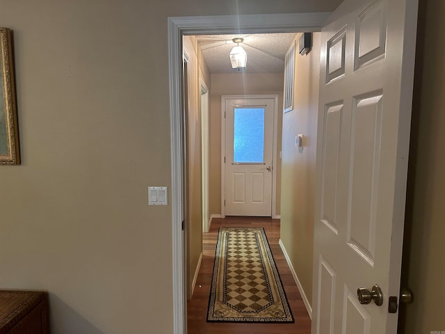 hall with a textured ceiling and dark wood-type flooring