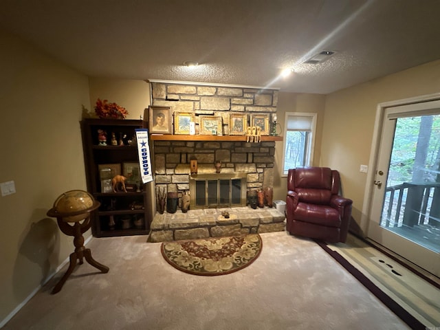 living area featuring a stone fireplace, carpet, and a textured ceiling